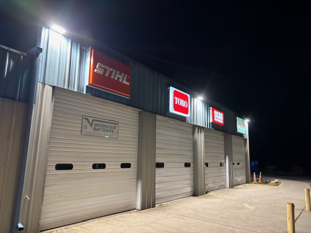 Commercial storefront with illuminated brand signage and exterior lighting at night