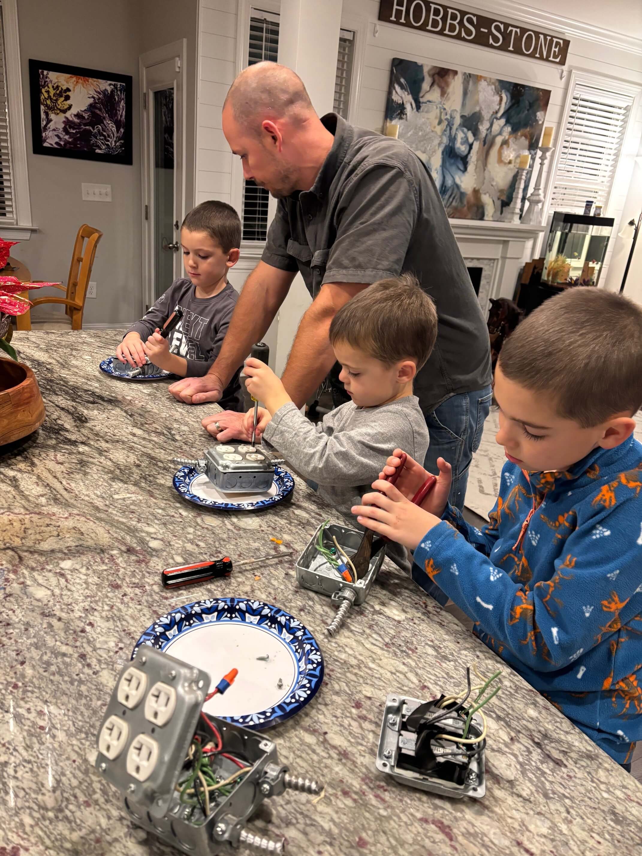 Stephen Hobbs-Stone teaching his sons how to wire receptacles at the kitchen counter