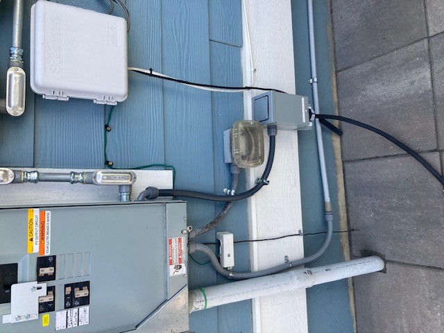 Residential generator interlock kit installed on exterior electrical panel with inlet box
